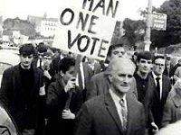 Image of a civil rights march in Londonderry, 5 October 1968, with a protest banner saying One Man, One Vote