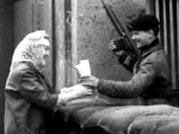 Image of  an old woman handing a cup of tea to a British soldier